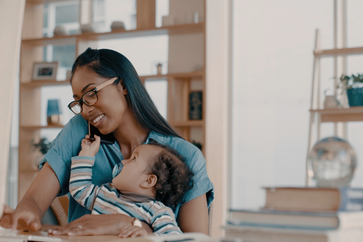 a woman holding a baby while looking at a computer