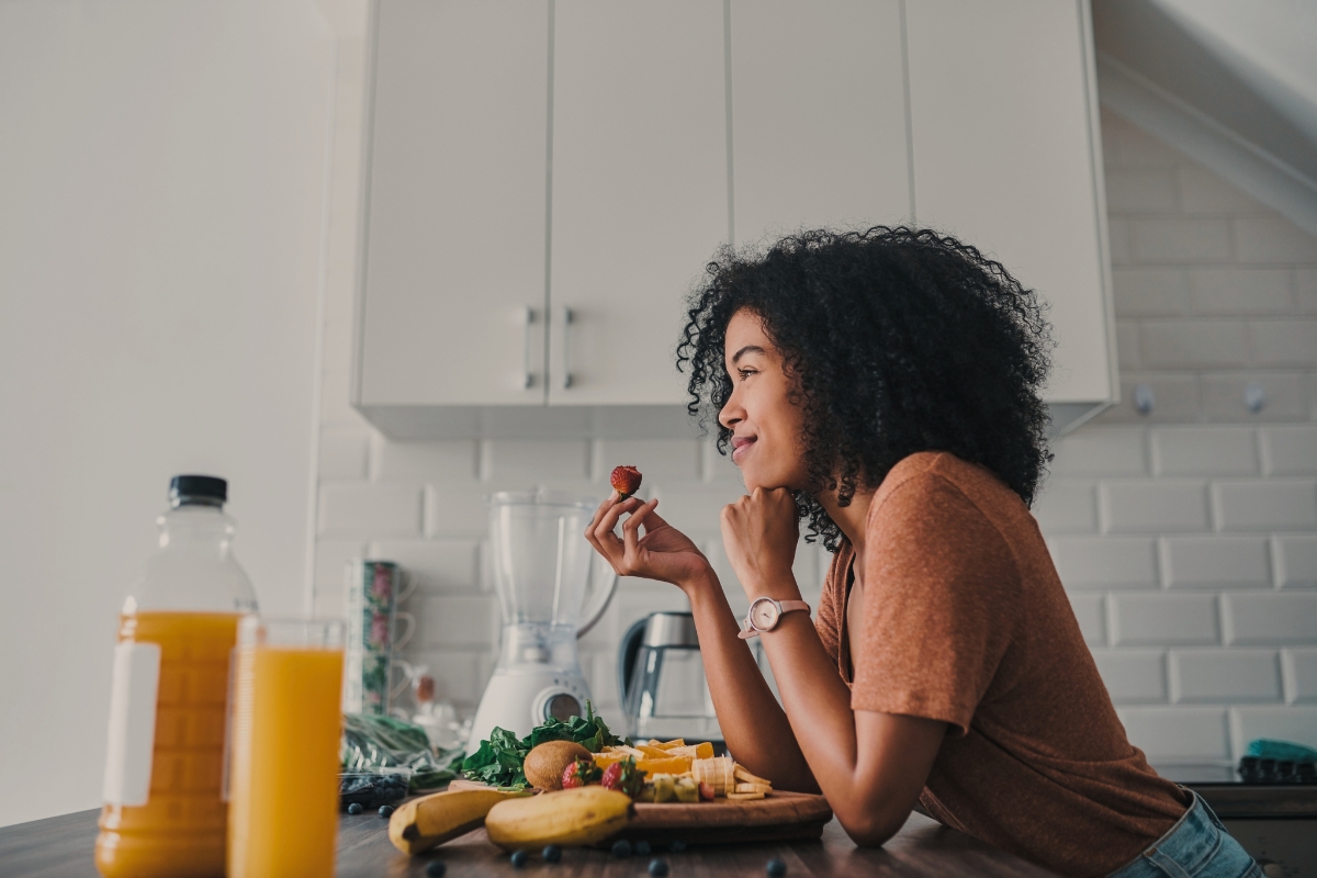 a woman eating a piece of fruit in the kitchen