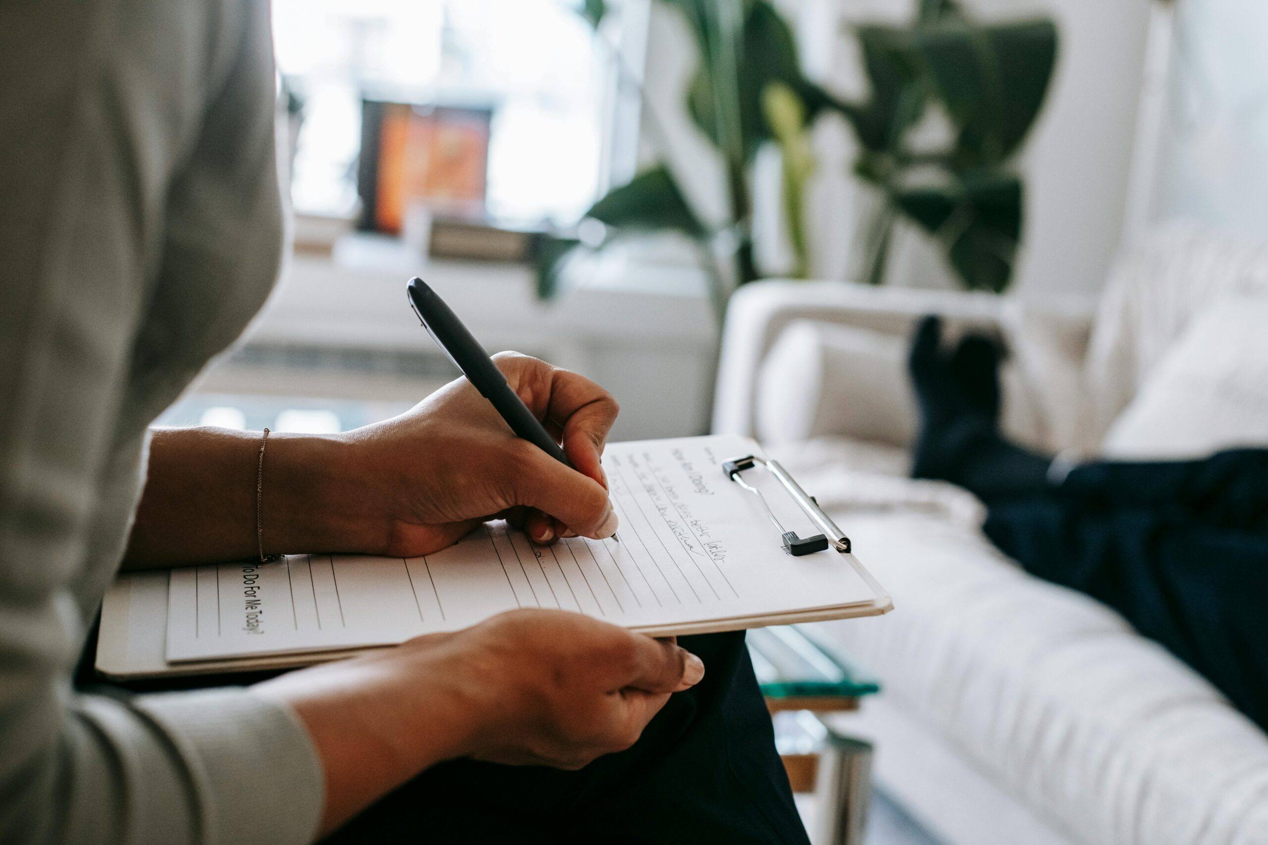 a person writing on a notebook with a pen in a living room