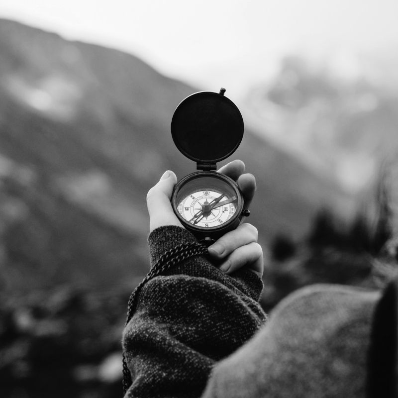 Hand holding a compass pointing north